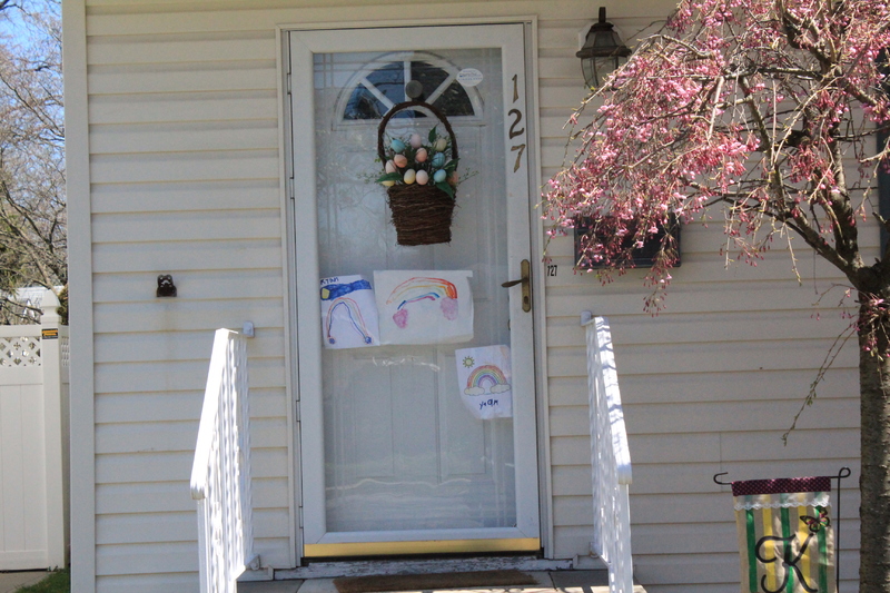 Residential house with three rainbow drawings place on the front screen door. 