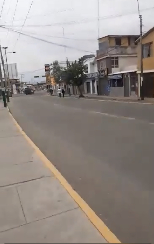 This is a picture of a quiet street with few people outside. 