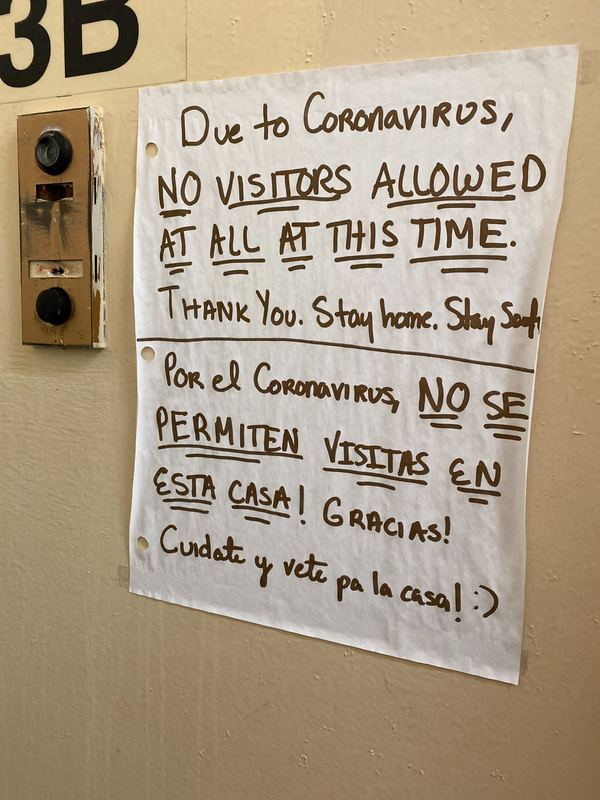 A hand written sign in English and Spanish that says "Due to Coronavirus, no visitors allowed at all at this time. Thank you, stay home, stay safe."