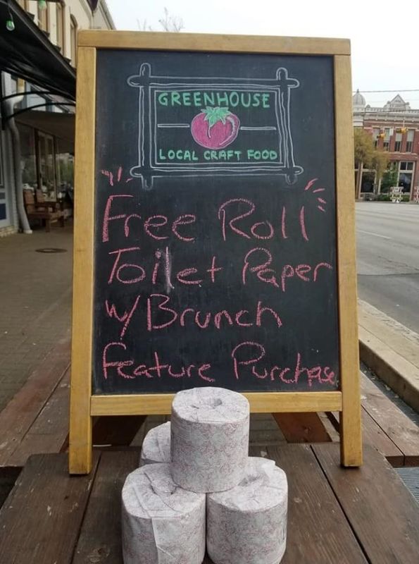 Image of a local restaurant chalkboard sign with a stack of toilet paper in front of it which reads free roll of toilet paper with brunch.