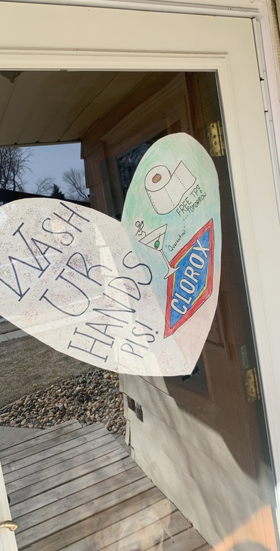 A paper heart that is taped to the inside of a front door that says: Wash UR HANDS PLS