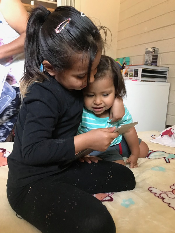 Two children look at a tablet screen.