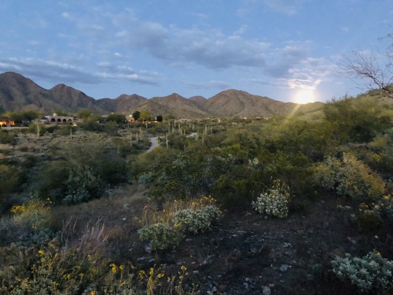 The moon rising near some mountains. 