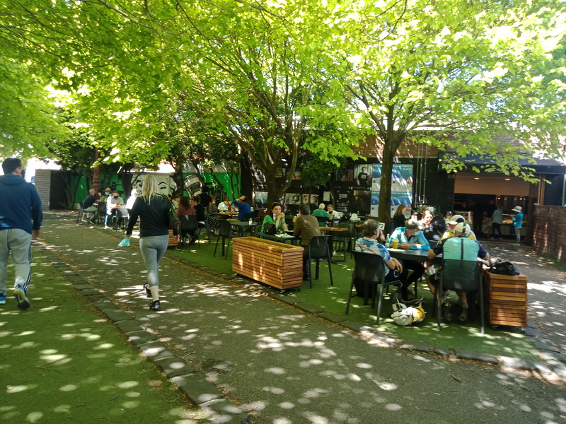 A picture of people sitting at tables outside at a restaurant. 