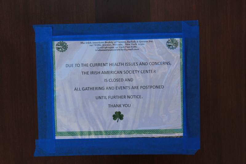 A sign that says "Due to the current health issues and concerns, the Irish American Society Center is closed and all gathering and events are postponed until further notice. Thank you."