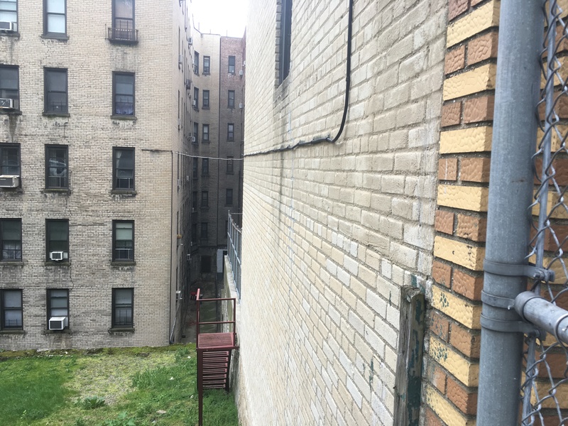 The side of a brick building with a green patch of grass below.