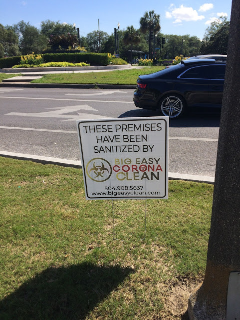 A sign in a grass patch next to a road. 