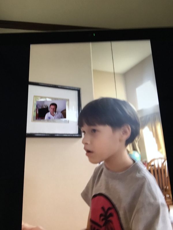 Boy with framed photo behind him of piano teacher.