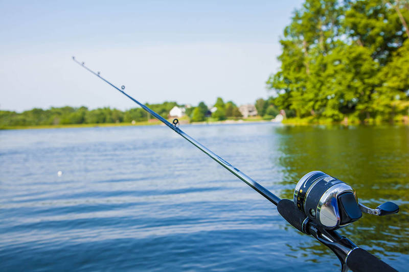 A fishing pole with a dark blue lake.