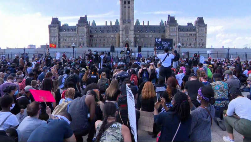 This is a picture of a group of people in a European country protesting for the Black Lives Matter movement in front of a cathedral. 