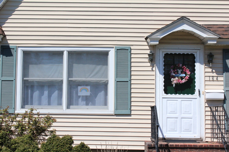 A residential house with a rainbow on the front window.