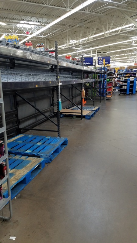 An aisle in a supermarket that has nothing on the shelves. 