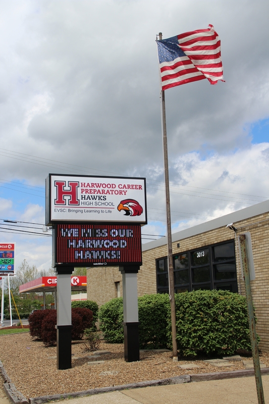 A sign outside a school reading "we will miss our Harwood Hawks".