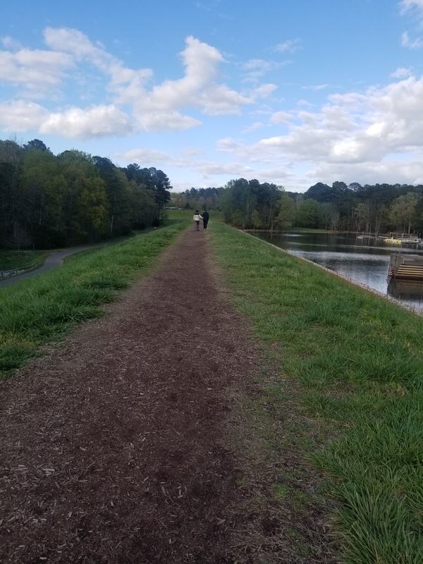 Two people walking along a dirt path. 