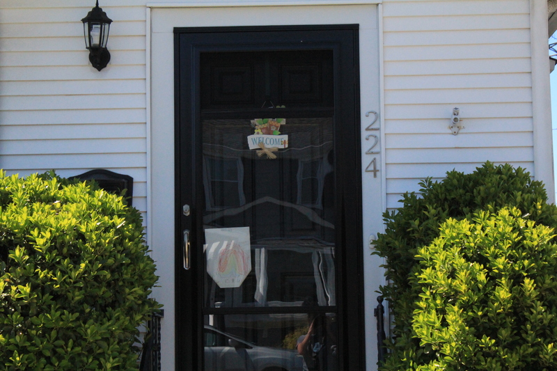 Residential house with a drawing of a rainbow on the front screen door. 