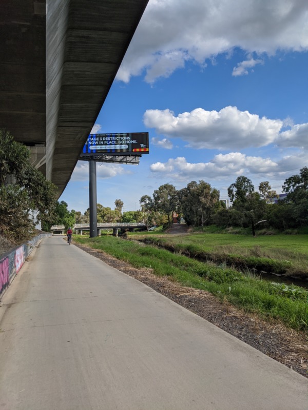 A sidewalk underneath an overpass.