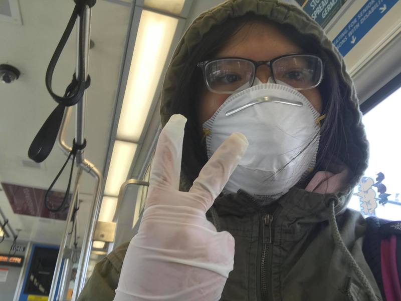 A person with a mask and glasses on public transportation.