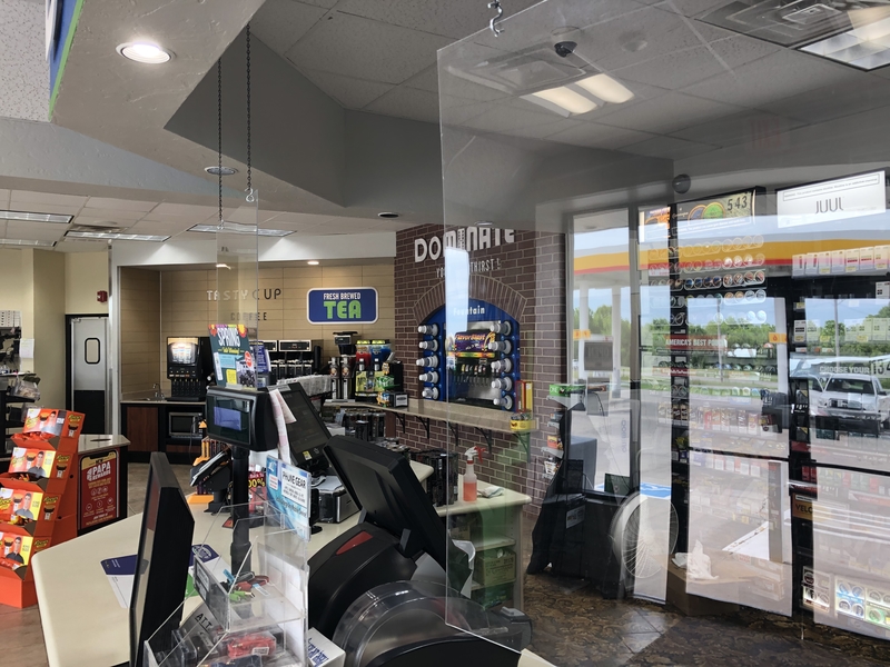 A photo of a checkout counter in a store with a plexiglass divider between the customer side and the cashier side.