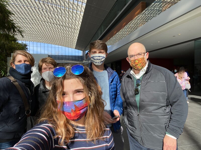 This is a picture taken of what appears to be a family dressed in winter clothing, wearing face masks in a public place.