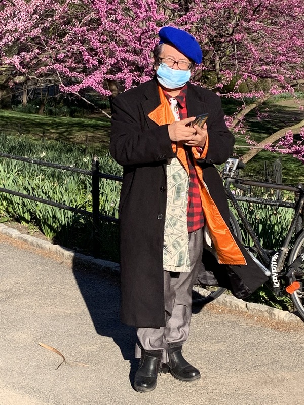 An old woman with her mask on in a park. 