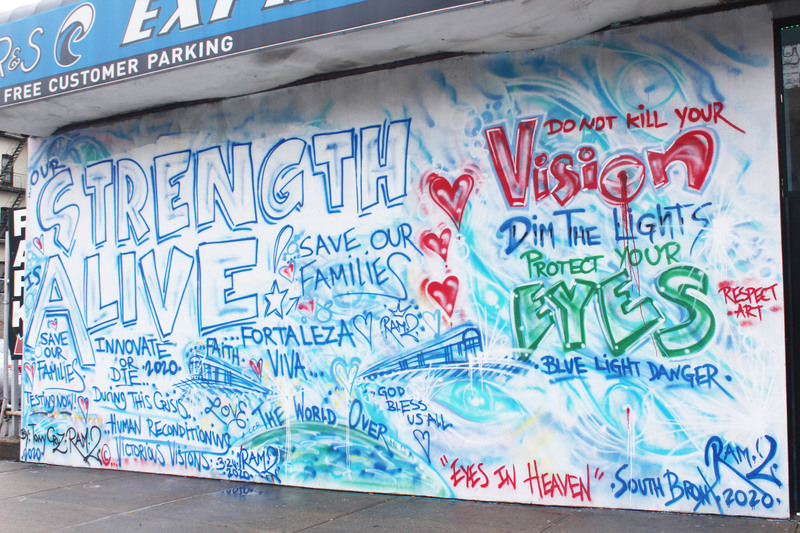 A mural with blue writing on the side of a building.