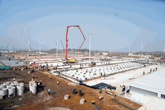 A photo of a large construction project with workers and a crane in the background.