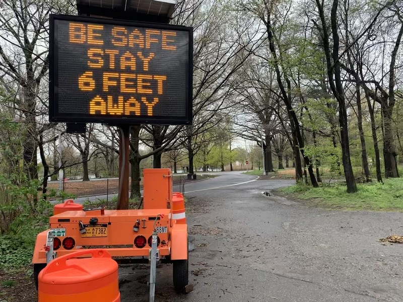 an orange neon sign telling people to stay 6 feet apart