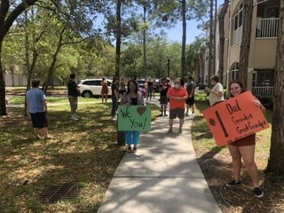 people hold signs saying "I love you" and " I miss you