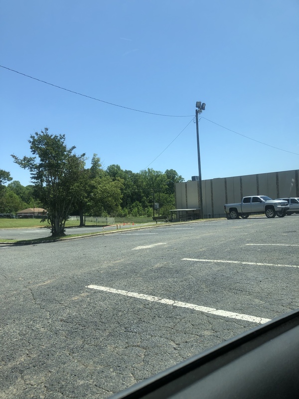 Mostly empty parking lot with only one truck and one SUV in the right side of the photo. 