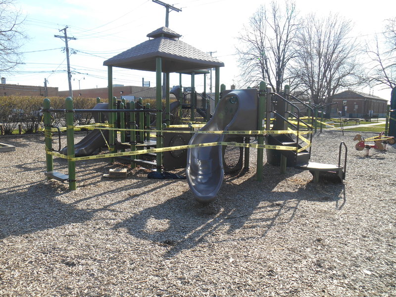 A playground that is blocked off with yellow caution tape. 