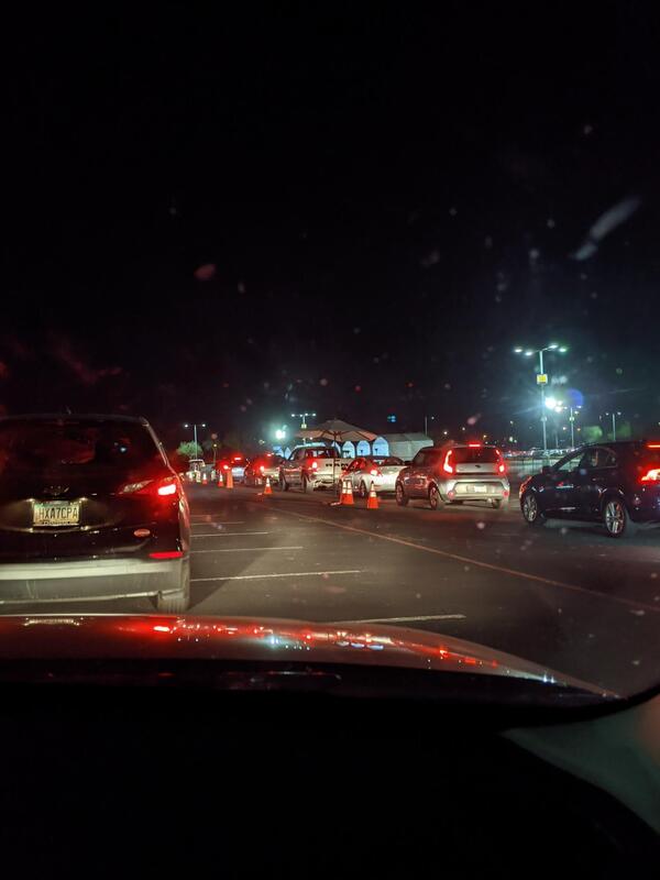 Line of cars at night at drive-thru COVID-19 vaccination site.