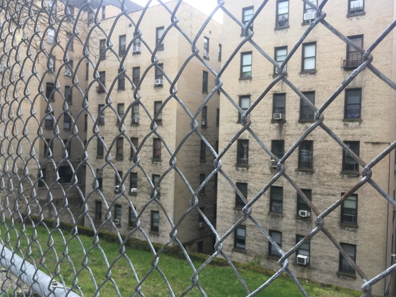 3 brick buildings behind a metal gate.