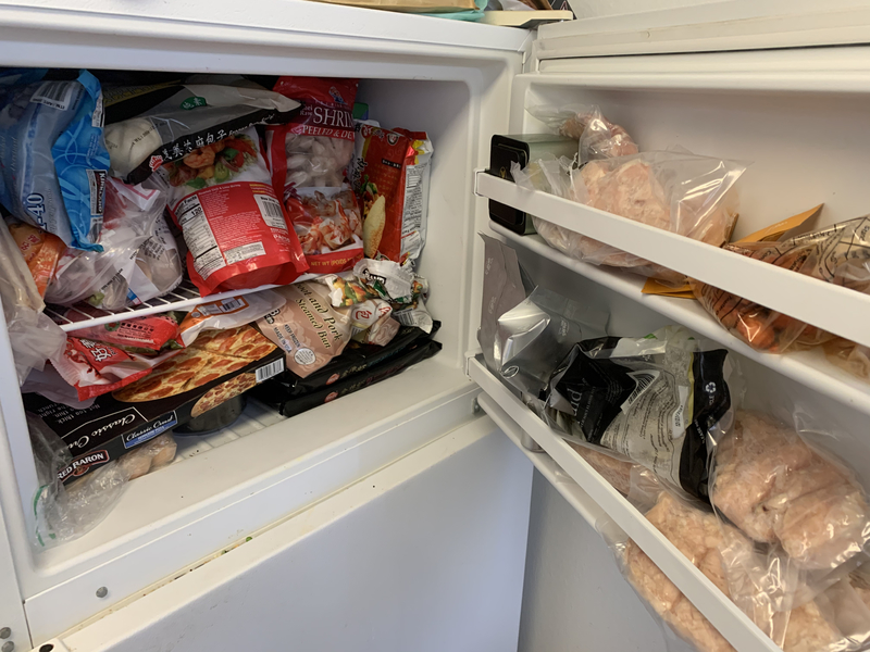 A freezer in a kitchen that is stocked full. 