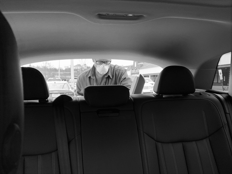 A man putting things in the trunk of a car. 