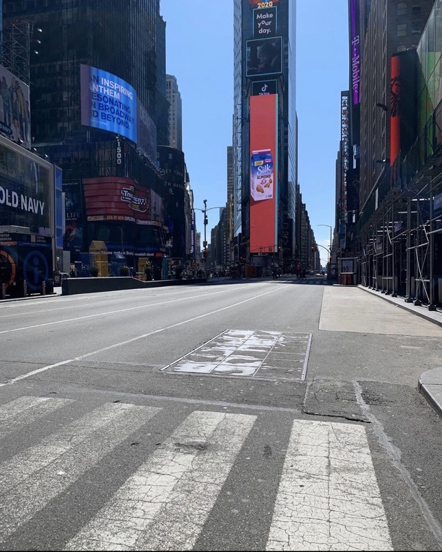 Times Square in New York City, New York complete empty. Billboard in the top right of the photo with text, "AN INSPIRING ANTHEM RESONATING IN BROADWAY AND BEYOND." Another billboard in the middle, top of photo with text, "Make your day."