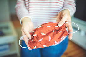 A woman holds a face mask. 