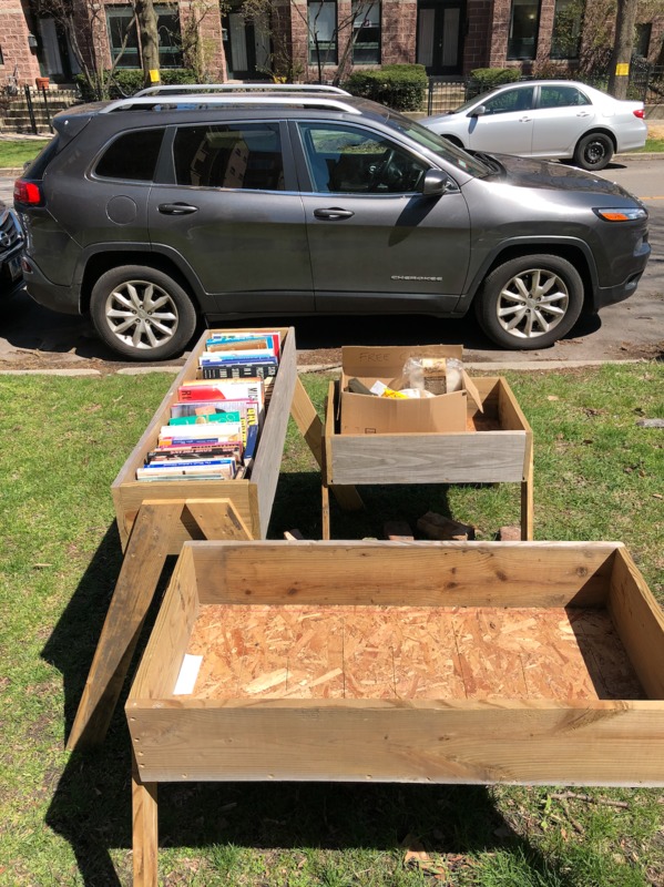 wood boxes with books in them on the side of the road