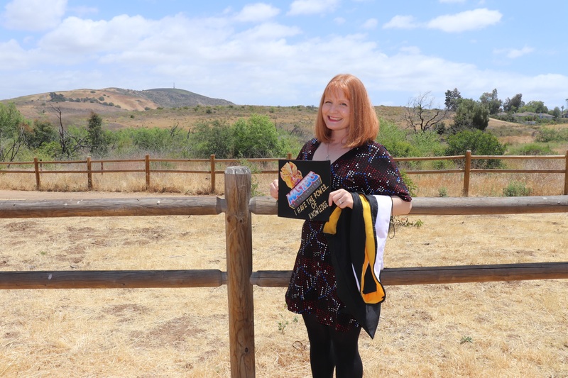 This is a picture of a woman who is wearing graduation clothing, posing for a picture in a desert landscape.