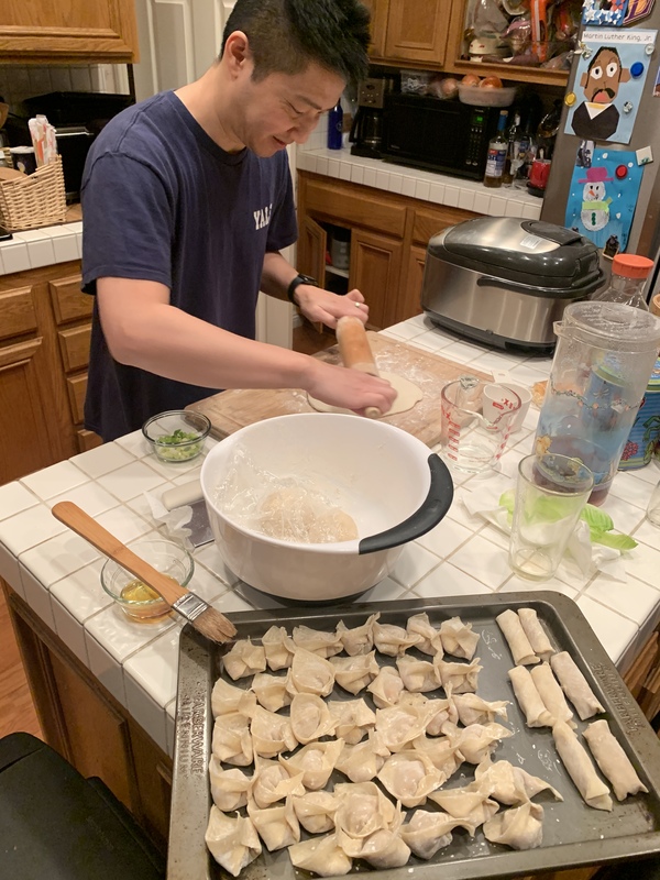 This is an image of a man who is flattening dough with a rolling pin to use in cooking. 