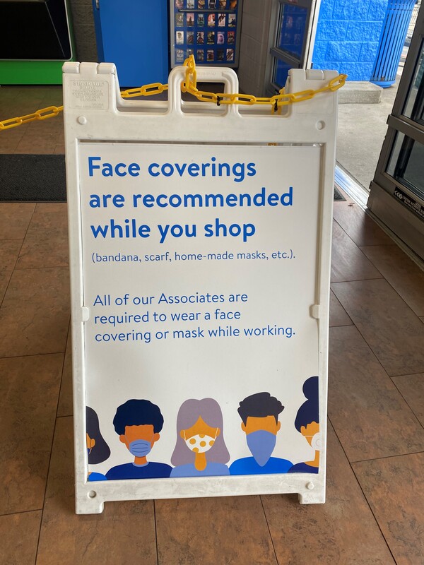 A sign reading "Face Coverings are Recommended While You Shop".