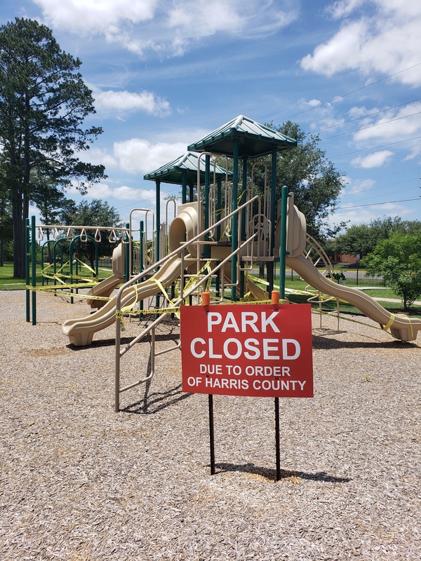 A red sign in front of a playground. 