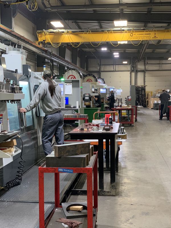 A workshop that is full of machinists standing at machines fixing them. 