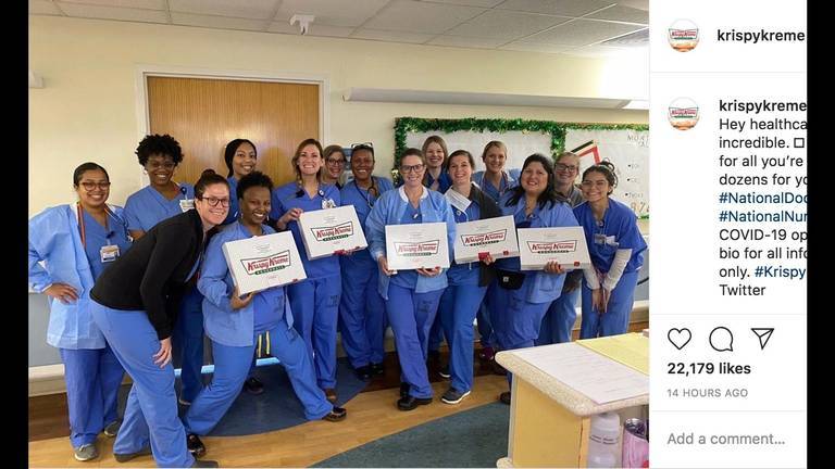 A photo of a group of healthcare workers holding Krispy Kreme donut boxes.