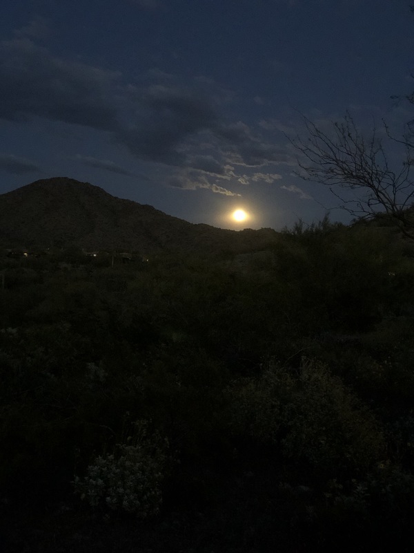 The moon rising near some mountains. 