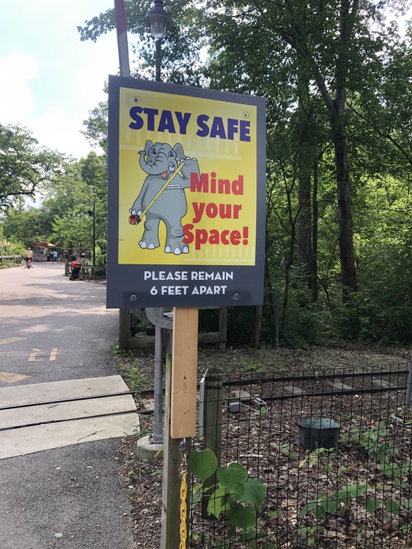 Photo of a sign featuring an elephant directing people to social distance. 