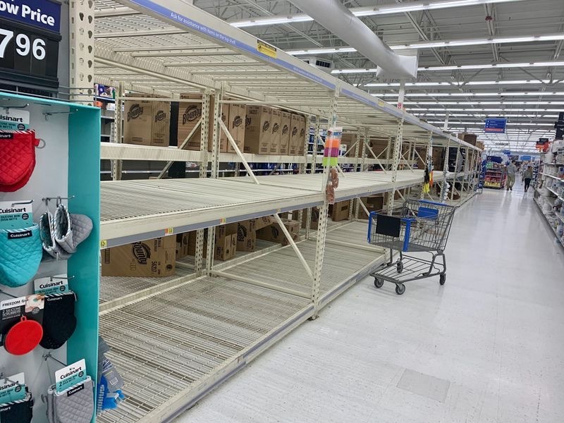 An aisle in a supermarket that has nothing on the shelves. 