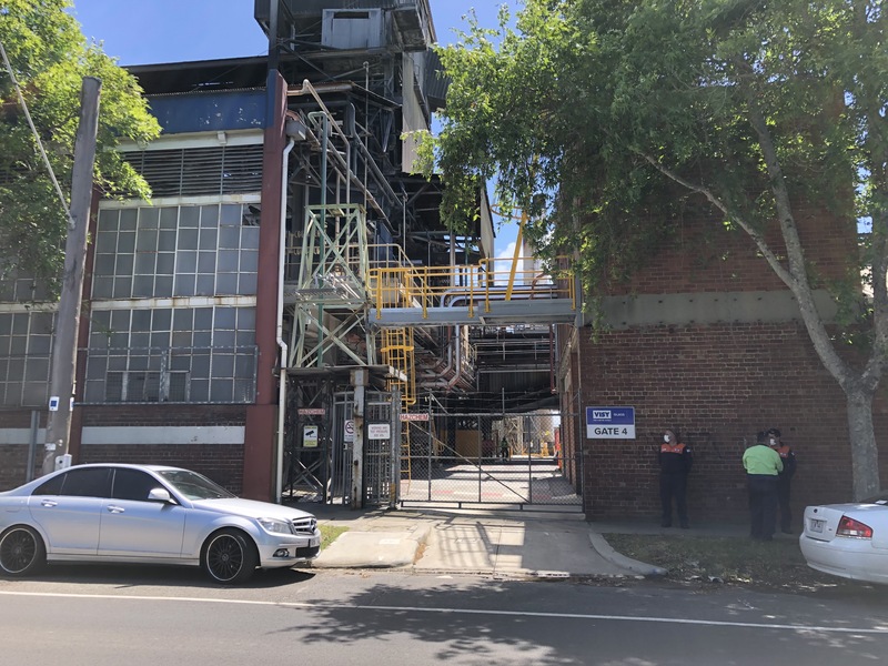 Picture of people wearing masks in front of a factory in Australia. 