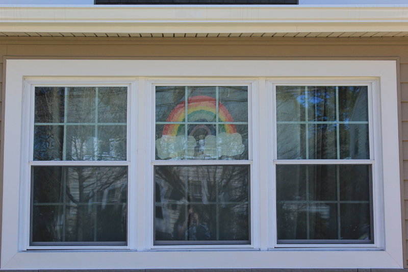 A residential house with a rainbow on a window.