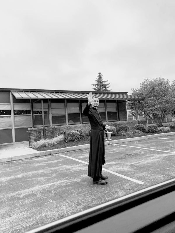 A priest in the street waving. 