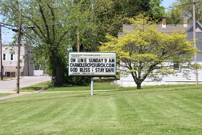 A sign reading "On Line Sunday 9 AM chandlercpchurch.com, God Bless, Stay Safe".